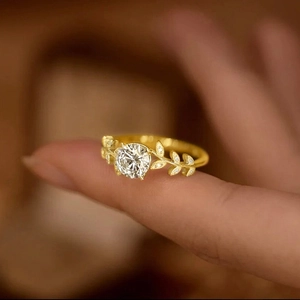 Close-up of golden laurel branch ring with brilliant round cut stone and diamond accents
