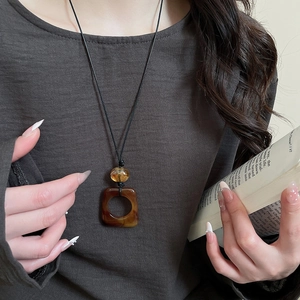 Detail of a brown leopard print resin pendant necklace worn with a minimalist cord