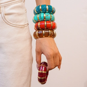 Detail of colorful geometric acrylic resin bangles with gold spacers on female wrist