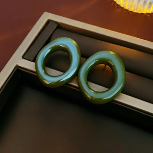 Detail of green resin circular stud earrings displayed on a brown jewelry tray