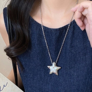 Detail of star-shaped necklace pendant with colorful stones and butterfly engraving on silver chain