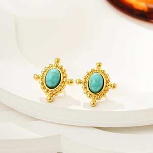 Macro shot of vintage gold earrings with oval turquoise inlay and beaded edge detail