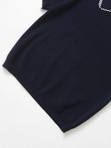 Detail of navy knit top featuring white scallop trim on collar and ribbed hemline