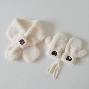 Detail view of plush beige winter scarf and gloves set with brown bear embroidery