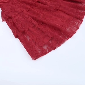 Detail view of multi-layered red lace floral patterns and textured embroidery on dress hem