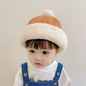 Detail of warm brown suede children's winter hat with soft cream plush trim and pom-pom