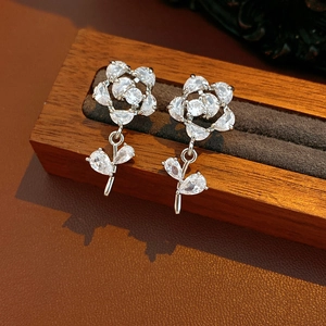 Détail de boucles d'oreilles fleur avec zircons et tiges en argent sur support