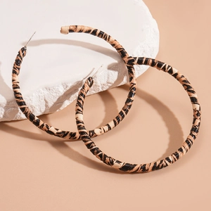 Retro leopard print geometric hoop earrings on textured white stone with beige background