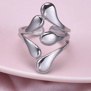 Macro detail of silver irregular hollow waterdrop ring on soft pink silk background