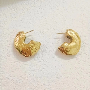 Detailed macro view of 18K gold plated hollow C-shape earrings with lava hammered texture