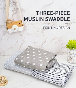 Three-piece muslin baby swaddle set featuring polka dots and chevron on marble surface