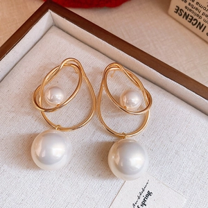 Gros plan détaillé de boucles d'oreilles anneaux dorés avec perles blanches sur plateau
