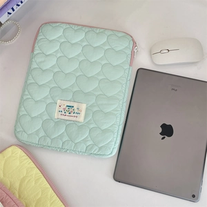 Detalle de la funda de iPad verde menta con diseño acolchado de corazón y etiqueta Happy