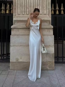Elegant white satin slip dress with lace trim shown on a model in a classic street setting