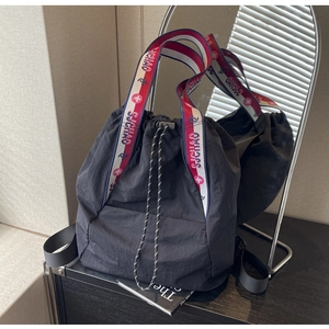 Detalle de bolso saco negro con correa de hombro a rayas rojas blancas y azules