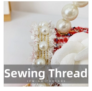Close-up of red and white tweed bag with golden thread and decorative pearl handle