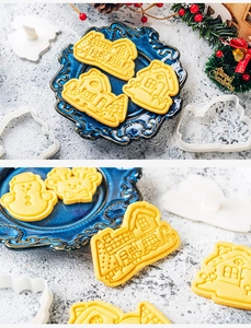 Detail of Christmas house and snowman shaped cookie cutters with baked biscuits on a festive table