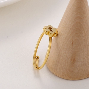 Vue détaillée d'une bague trèfle dorée réglable sur un support en bois minimaliste