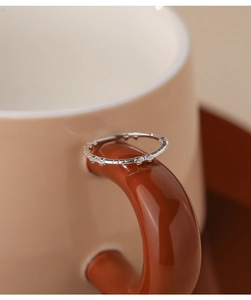 Close-up of S925 sterling silver bow ring displayed on a ceramic mug handle