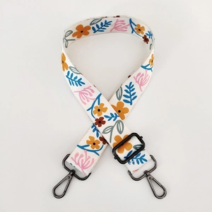Detail of adjustable floral print handbag strap with white fabric and black metal hooks