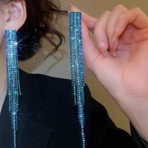 Macro view of square tassel earrings with blue and green crystals showing cascading chains