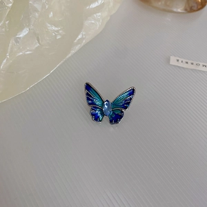 Close-up of enamel butterfly brooch with blue marquise gemstone and metallic edges