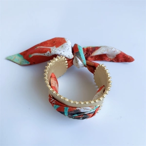 Matte gold open cuff bracelet with red and green floral silk scarf wrap and bow