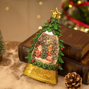 Christmas tree snow globe with Santa and reindeer on vintage books with festive lights
