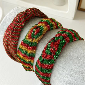 Three festive Christmas headbands with glitter stripes on a velvet display stand