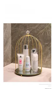 Detail of birdcage cosmetic rack with gold metal frame and mirrored base on marble surface