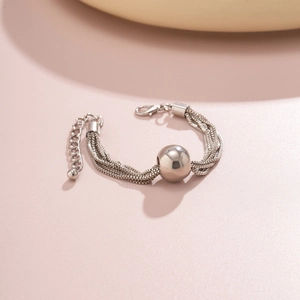 Detailed close-up of a silver multi-layered snake chain bracelet with round metal beads