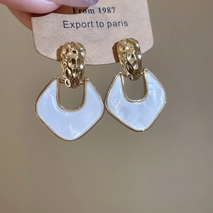Close-up of vintage geometric shield earrings with white pearlescent inlay and gold frame