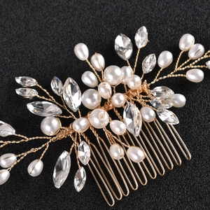 Dettaglio ravvicinato di pettine da sposa con perle, strass e foglie in filo dorato