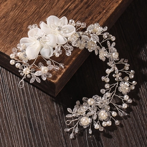 Elegant bridal hair comb with white fabric flowers, pearls and crystals on dark wood