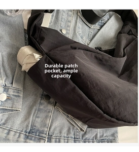 Detailed view of the side pocket on black nylon crossbody bag storing a folded umbrella