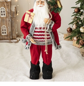 Detail of Santa Claus figure holding a yellow gift box near a miniature wooden house