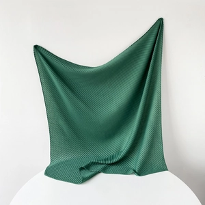 Detailed texture of dark green pleated cotton-linen square scarf with elegant folds
