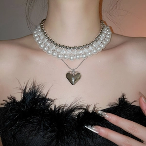 Détail d'un ensemble de colliers de perles blanches avec pendentif cœur argenté