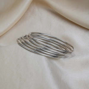 Close-up of minimalist silver stainless steel multi-layered bangles on champagne silk