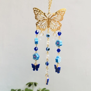 Detail of metal wind chime with gold butterfly, evil eye beads and blue flower accents