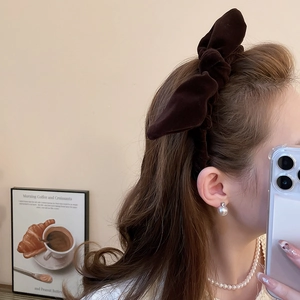 Close-up of a dark brown velvet knotted headband and elegant pearl jewelry set