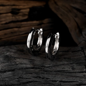 Macro shot of silver chunky hoop earrings on a textured black charcoal background