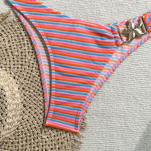 Detail of ribbed striped bikini bottoms with a gold starfish metal charm on the side