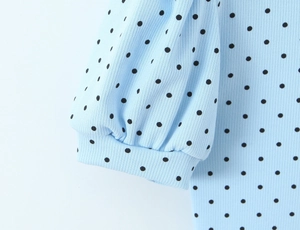 Detail of light blue polka dot romper showing ribbed fabric and puffed sleeve cuff