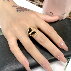 Detail of a golden titanium steel ring with black butterfly motif on model finger