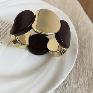 Detailed view of brown resin and gold metal geometric links on a white display plate