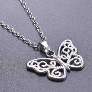 Macro detail of silver butterfly pendant with intricate hollow engraving on link chain