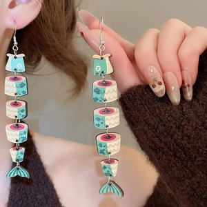 Detailed close-up of fish-shaped wooden print earrings with ethnic tassel pendant design