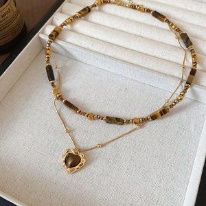 Detail of double-layer tiger eye bead necklace with a heart-shaped golden pendant