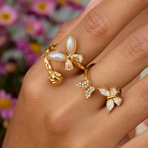 Close-up of dual butterfly rings in gold finish with pearls and shimmering zircons